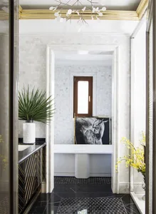 Modern, minimalist entrance hall with marble finishes, a chandelier, and a horse portrait.