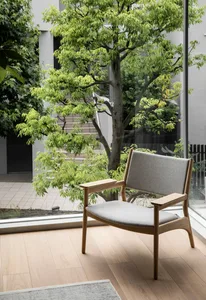 Modern minimalist living room with wooden furniture and greenery outside the window.