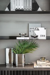 Modern, metal bookshelf display with books, plants, and decorative items.