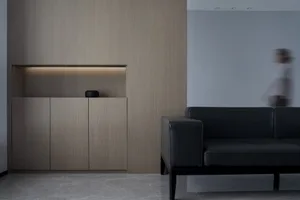 An interior design showcasing a minimalist living room with wood shelving, a leather sofa, and marble flooring.