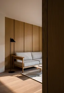 A modern minimalist living room featuring a gray sofa, wooden floor, and wooden panel wall.