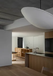 A modern residential kitchen with wooden furniture and concrete ceiling.