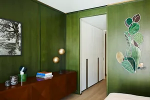 A modern bedroom with green textured walls, wooden floors, and a white bed.