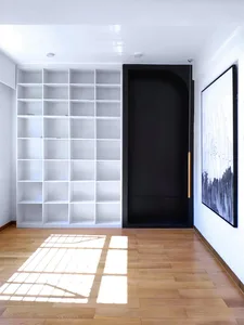 Modern minimalist interior design featuring an empty white shelf with a black door and a large abstract painting.