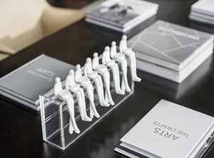 A minimalist working space with white plastic figurines and books on a dark surface.