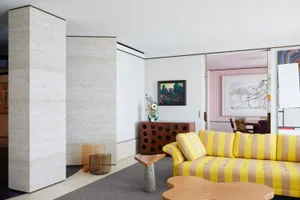 A modern living room featuring concrete walls, wooden furniture, and metal accents.