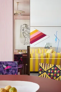 A modern living room featuring vibrant yellow striped sofas and colorful chairs.
