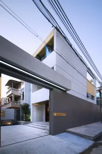 A modern, minimalist residential facade featuring concrete and glass materials.