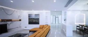 Modern minimalist living room with white marble floor, orange sectional sofa, and black coffee table.