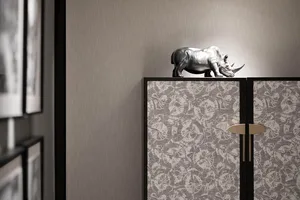 Modern bedroom interior with floral pattern walls and silver rhinoceros statue on cabinet.