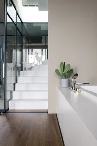 A minimalist interior with white stairs featuring a concrete floor and two decorative chickens.