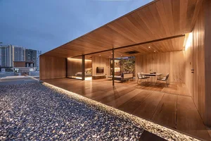 A modern living room with wooden flooring and ceiling, featuring a cozy seating area, a dining table, and a television.