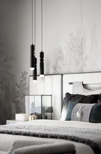 Modern minimalist bedroom featuring textured fabric bedding, wooden headboard, and metal pendant lights with botanical print 