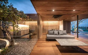 A modern living room with wooden flooring and walls, featuring a gray sofa and a marble coffee table.