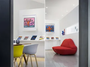 A modern white living room featuring a red curved sofa and wooden floor.