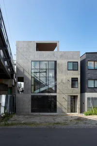 Modern concrete house with large windows and concrete exterior.