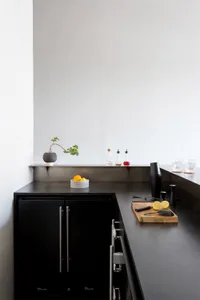 A minimalist kitchen counter featuring metallic surfaces and black cabinets.