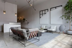 A minimalist living room featuring concrete furniture, metal accents, and fabric upholstery.