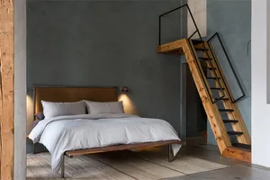 A minimalist bedroom with a wood-frame bed, white bedding, and a dark gray wall.