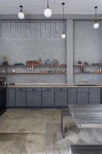 A modern, industrial-style kitchen with concrete cabinets and minimalist design.
