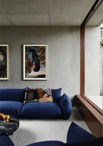 Minimalist lounge area with a blue sofa, concrete walls, and framed art.