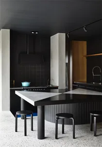 Modern kitchen with concrete flooring, black cabinets, and a black triangular table with black stools.