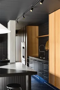 A modern kitchen interior with concrete flooring and wooden cabinets.