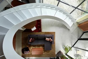 A modern living room features a metal staircase and concrete floor.