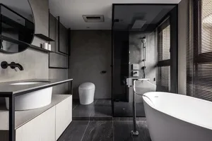A modern bathroom featuring concrete walls, a freestanding bathtub, and a glass-enclosed shower.