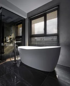 A modern bathroom featuring a freestanding bathtub, a glass-enclosed shower, and black blinds on the window.