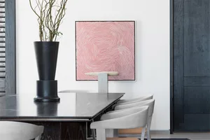A modern dining table made of concrete with white chairs and a red and white abstract painting.