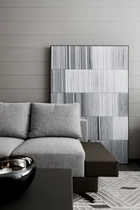 Modern grey sofa in a contemporary living room with abstract wall art and a geometric rug.