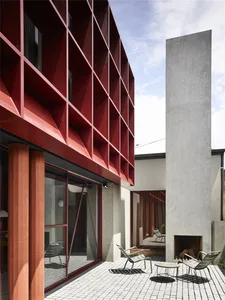 A modern house exterior with red concrete and metal accents.