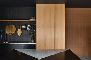 Modern kitchen with wooden cabinets, black backsplash, and a stone countertop.