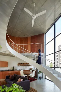 Modern living room with concrete walls, wooden furniture, and large windows