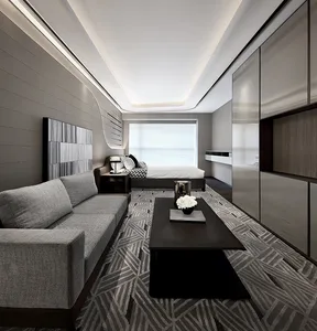 A modern minimalist bedroom featuring a grey couch, a black coffee table with white flowers, and a neatly made bed.
