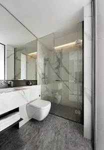 Modern minimalist bathroom with marble finishes and glass shower enclosure.