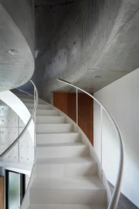 Modern, minimalist staircase with concrete walls and white steps.