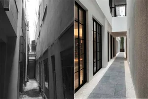 Renovated building with concrete walls, large glass panels, and metal railings.