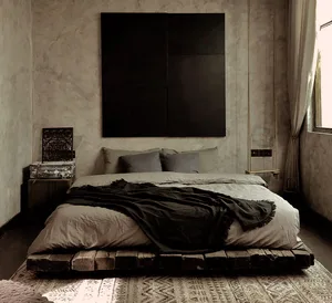 A modern industrial-style bedroom with a wooden pallet bed, concrete walls, and a minimalist art piece.