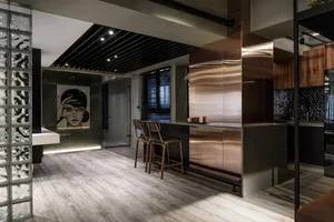 A modern kitchen with concrete flooring and wooden elements, featuring stainless steel appliances and a minimalist design.