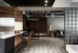 A modern living room with metallic decor, including a sleek bar counter and chairs, a cozy seating area with a sofa, and a st