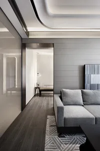 Modern minimalist living room featuring sleek gray sofas, wooden flooring, and contemporary decor.