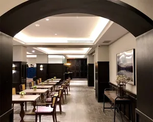 A spacious, modern restaurant interior with wooden tables and chairs, archways, and a warm, inviting atmosphere.