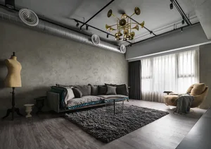 Modern industrial living room with concrete walls, grey sofa, and black coffee table on a grey rug.