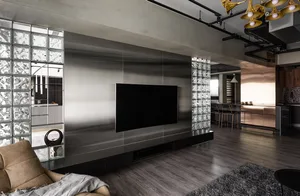 Modern metallic living room with a large TV on a black floating stand, surrounded by glass blocks and concrete walls.