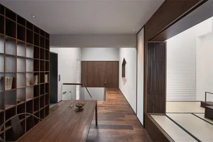 Modern minimalist living room with wooden elements, white walls, and a wooden table.