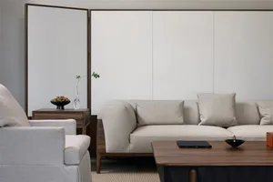 Modern minimalist living room featuring a white sofa with wooden legs, a wooden coffee table, and a side table with a vase an