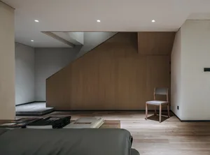Modern minimalist living room with wooden furniture and a chair.