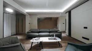 A modern living room with a leather sofa, marble coffee table, and minimalist decor.